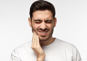 Man holding his cheek in pain before seeing an emergency dentist in Herndon