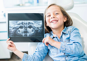 kid holding a dental x-ray printout