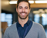 man wearing gray sweater, smiling