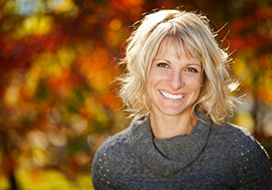 woman wearing sweater, standing by the trees